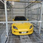 立体駐車場のパレットに収まる黄色いホンダ・S2000のフロントビュー