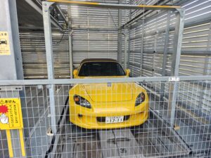 立体駐車場のパレットに収まる黄色いホンダ・S2000のフロントビュー
